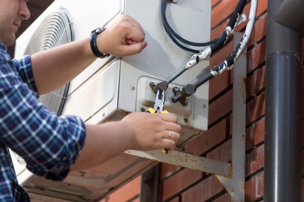 Closeup photo of male technician repairing outdoor air conditioner unit